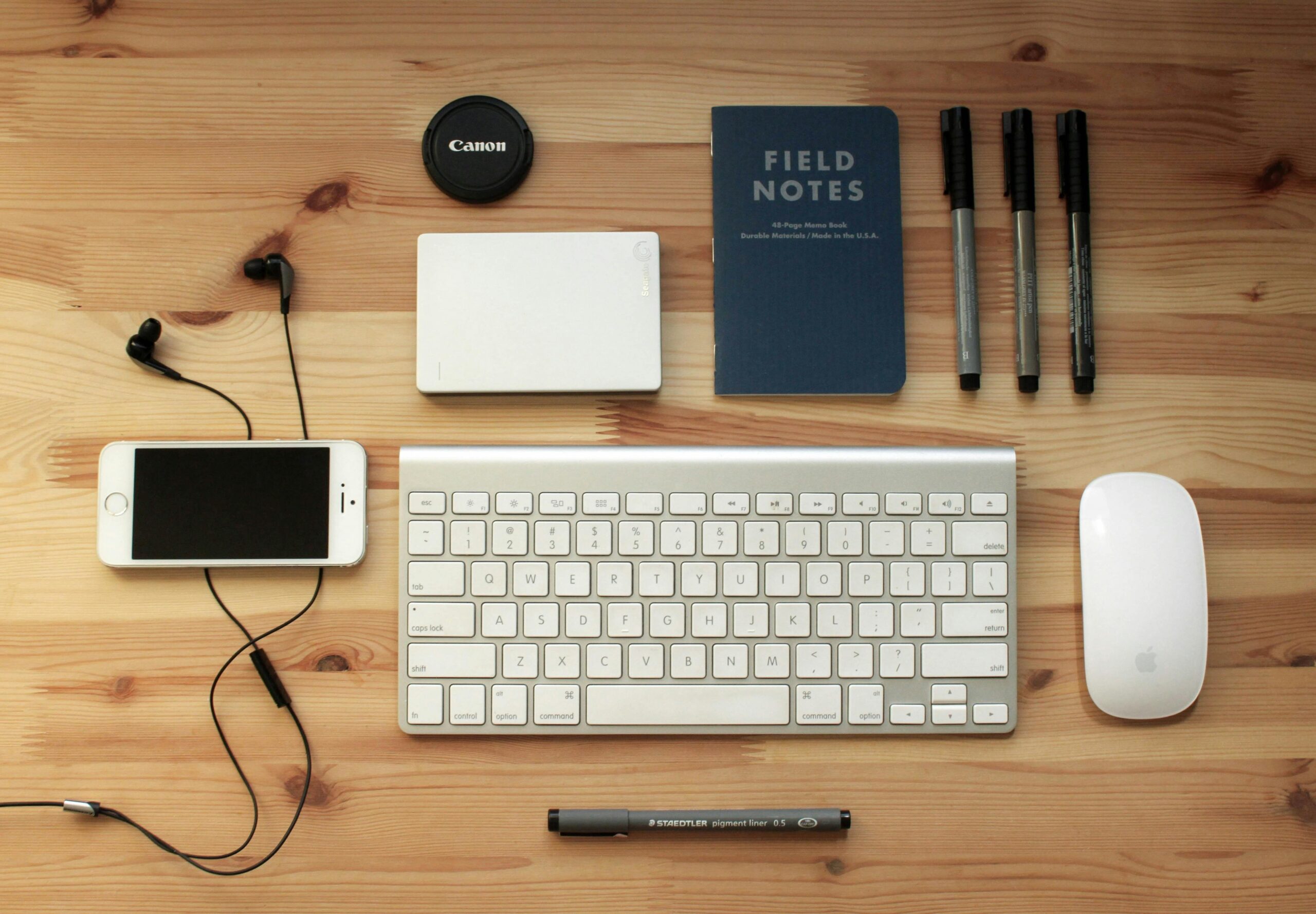 🔥 Popular Gadgets to Consider in India (2026) Top view of a modern desk setup featuring electronics, stationery, and gadgets on a wooden surface.