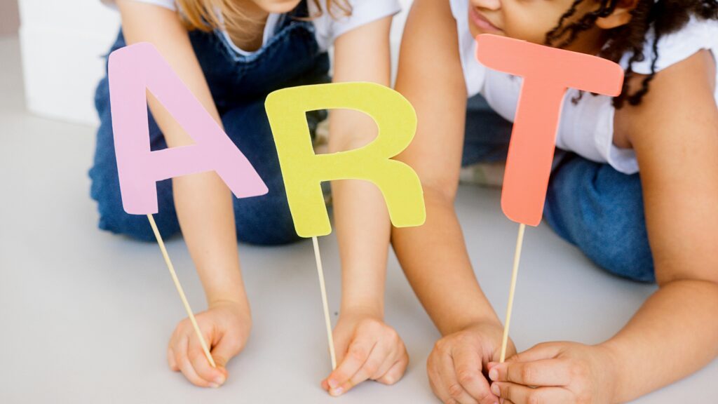 Children playing with colorful paper cutouts spelling 