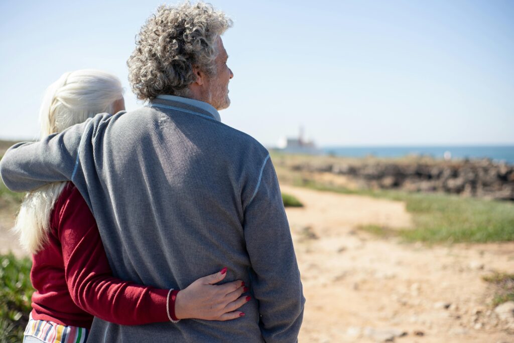 Senior couple sharing a warm embrace by the ocean in scenic Portugal.